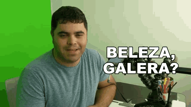 a man sitting at a desk with a green screen behind him and the words beleza galera written above him