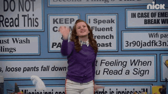 a woman is standing in front of a wall with signs that say do not read this