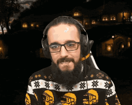 a man with a beard wearing headphones and a sweater that has the letter b on it