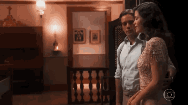 a man and a woman are standing next to each other in a room with a globe in the corner