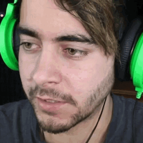 a man with a beard is wearing green headphones and looking at the camera .