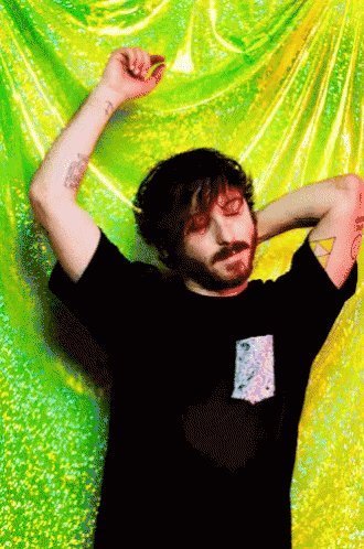 a man with a beard is standing in front of a green and yellow curtain