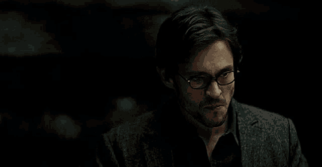 a man wearing glasses says that 's delicious in a dark room .