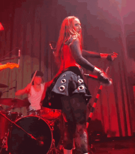 a man playing drums and a woman singing into a microphone on a stage