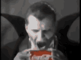 a black and white photo of a vampire eating a box of candy