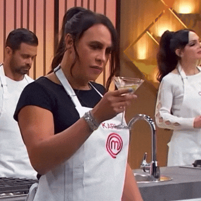 a woman wearing an apron with the letter m on it is holding a martini glass