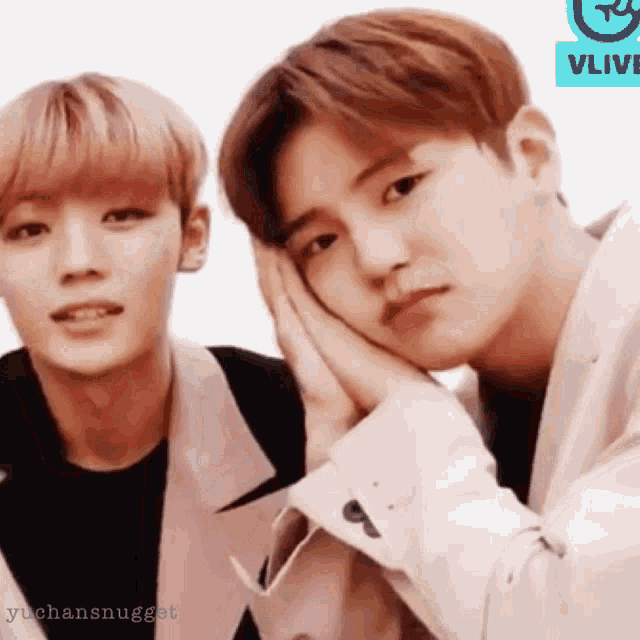 two young men are sitting next to each other and one of them is laying his head on the other 's lap .