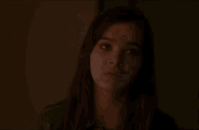 a close up of a woman 's face in a dark room looking at the camera .