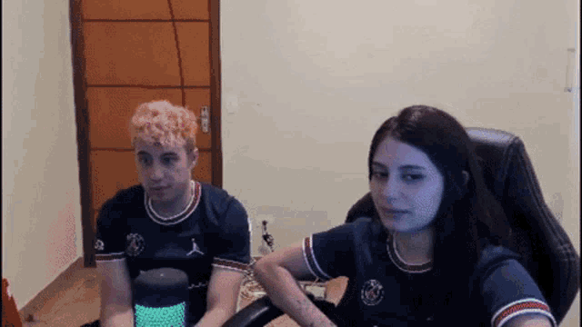 a man and a woman are sitting in front of a computer screen ..