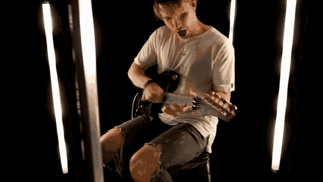 a man in a white shirt playing a guitar