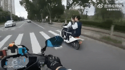 a man and a woman are riding a scooter on a street .