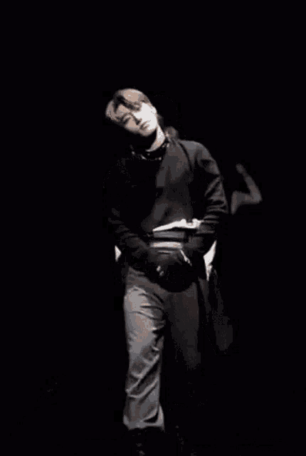 a man in a black and white outfit is dancing on a stage in a dark room .