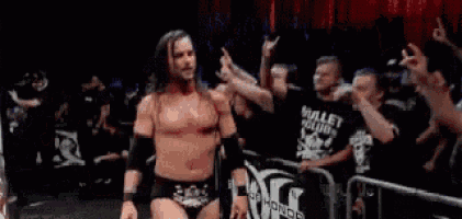 a man in a wrestling ring with a crowd behind him and a sign that says bullet club