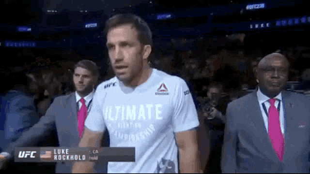 a man in a white shirt with the word ultimate on it is walking into a stadium .