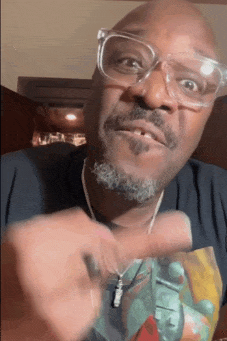a man wearing glasses and a necklace with a pendant that says ' supreme ' on it