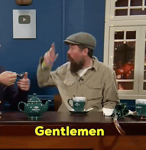a man with a beard is sitting at a table with the word gentlemen on the table