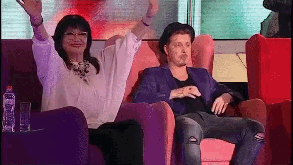a man and a woman are sitting in chairs with their arms in the air