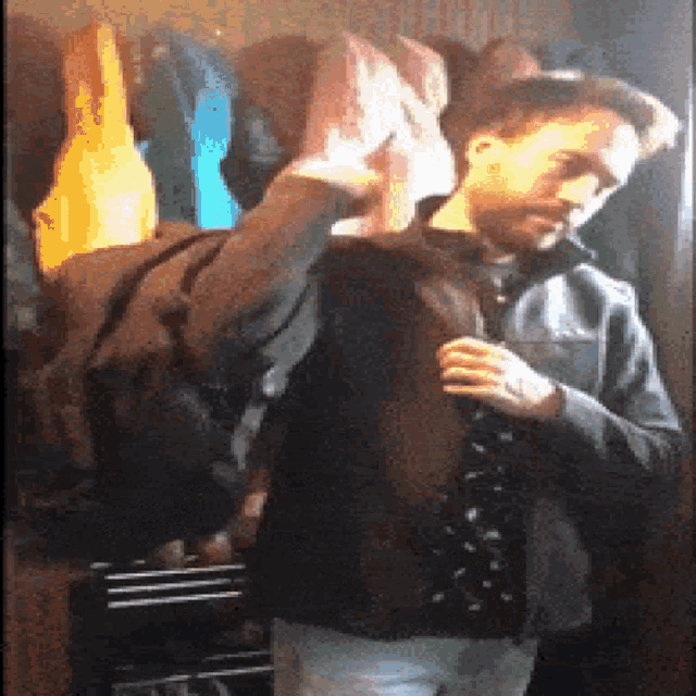 a man is adjusting his jacket in front of a mirror in a closet