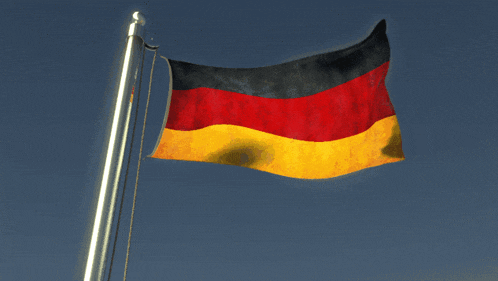 a german flag flies in the wind against a blue sky