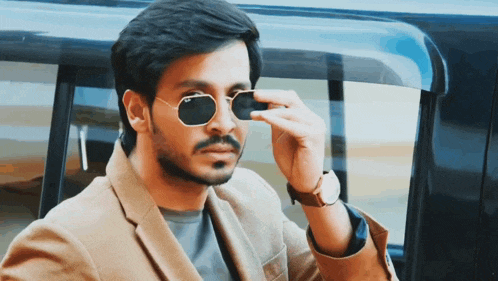 a man wearing sunglasses and a watch adjusts his glasses