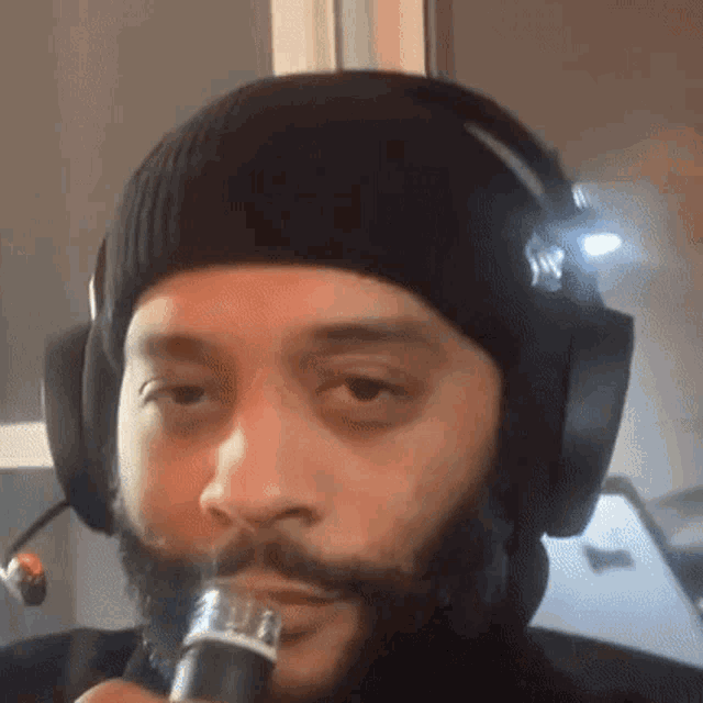 a man with a beard is wearing headphones and a beanie .