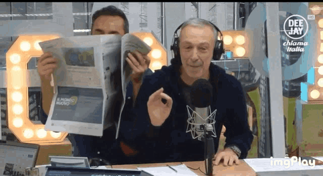 a man wearing headphones holds a newspaper in front of a deejay logo