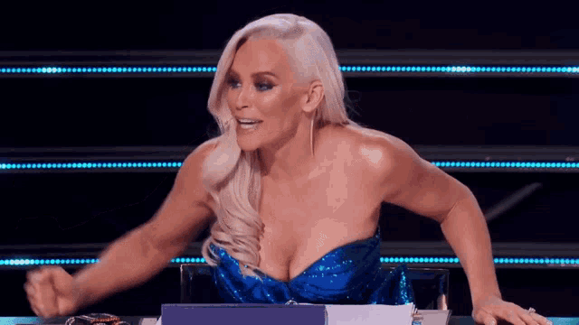 a blonde woman in a blue dress is sitting at a table