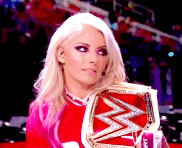 a woman in a pink outfit is holding a wrestling belt