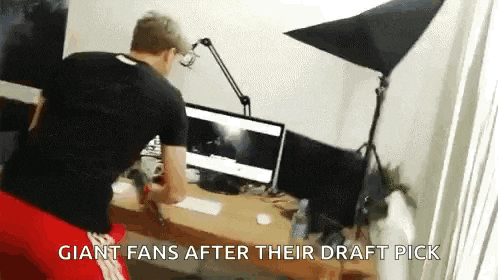 a man is sitting at a desk in front of two computer monitors with the caption giant fans after their draft pick