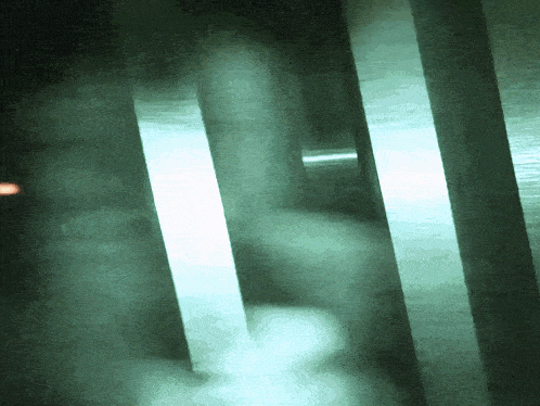 a blurred image of a person 's hand holding a light in a dark room