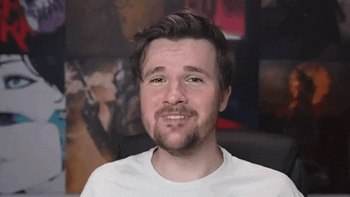 a man with a beard is making a funny face in front of a wall with pictures of women on it .