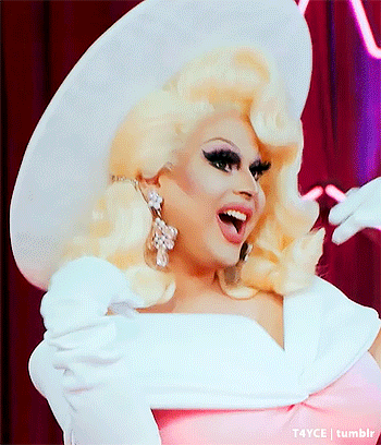a drag queen wearing a white hat and pink dress