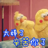 two stuffed chickens are sitting on a couch with chinese writing