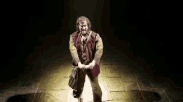 a man in a red vest is dancing on a stage in a dark room .