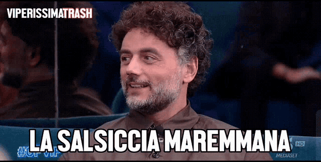 a man with curly hair and a beard is smiling and says la salsiccia maremmana
