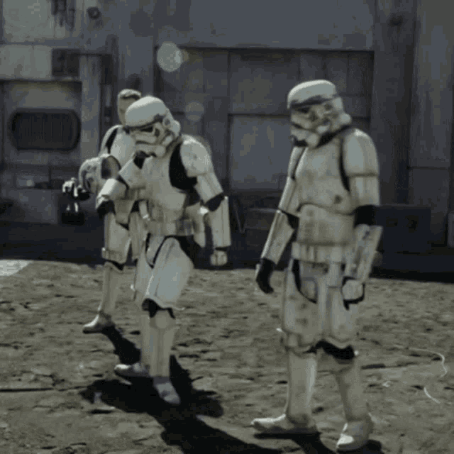 three stormtroopers are standing on a dirt ground