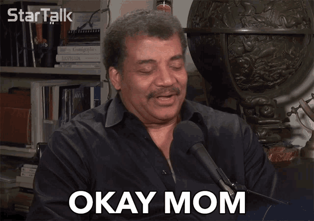 a man talking into a microphone with the words okay mom below him