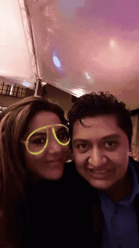 a man and a woman wearing glow in the dark glasses pose for a photo