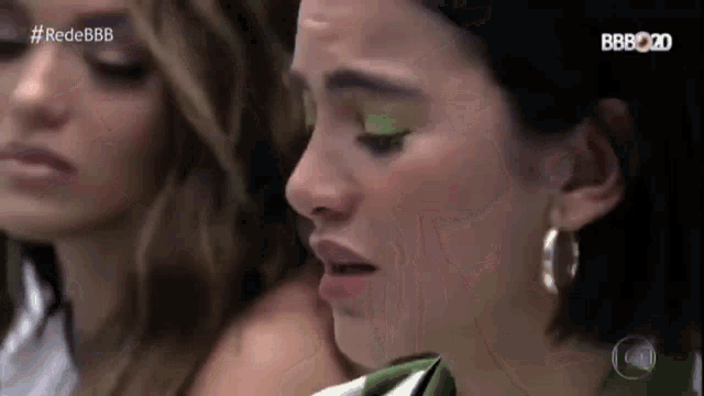 two women are sitting next to each other and one of them has green eye shadow on her eyes .