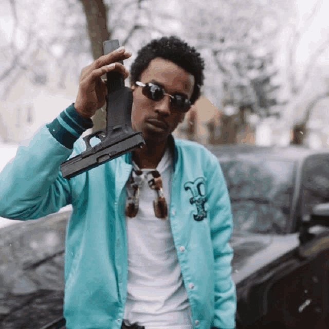 a man in a blue jacket holds a gun over his shoulder