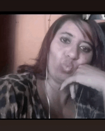 a woman wearing a leopard print shirt and ear buds blowing a kiss