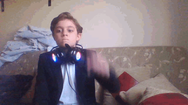 a young boy wearing headphones and a tuxedo sitting on a couch
