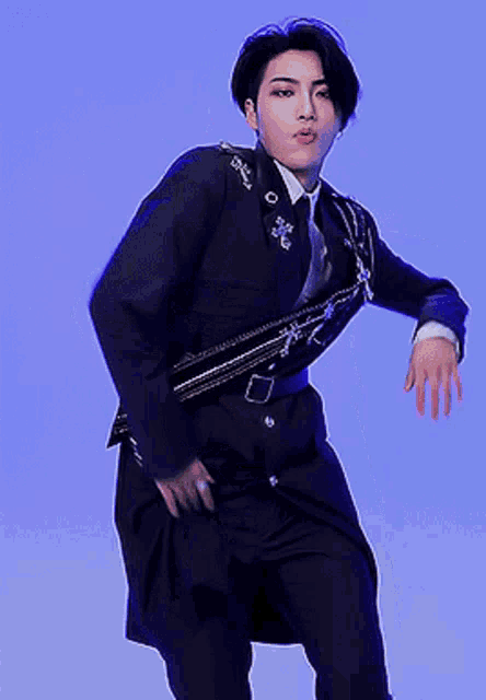 a young man in a suit and tie is dancing in front of a blue background .