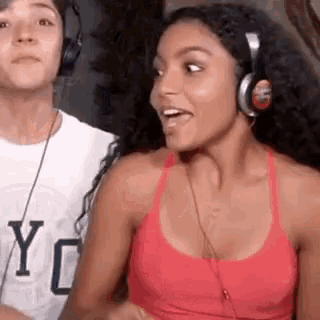 a woman wearing headphones and a red tank top is standing next to a man .