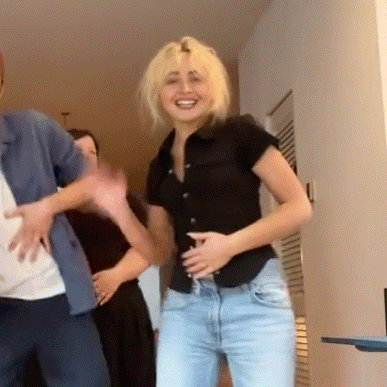 a woman in a black shirt and blue jeans is dancing with a man