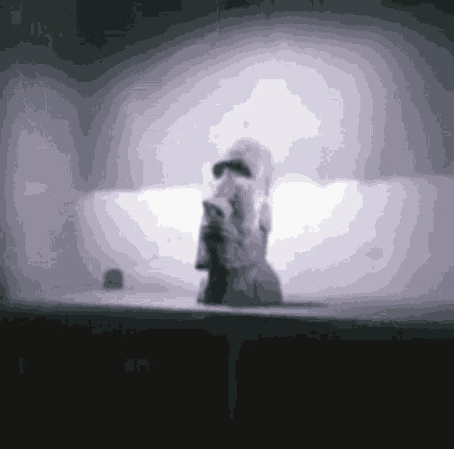 a black and white photo of a person standing in a dark room holding a microphone .