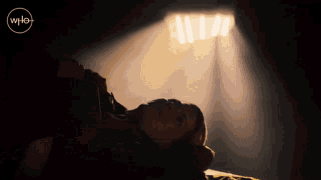 a woman is laying down in a dark room with the word who on the bottom right