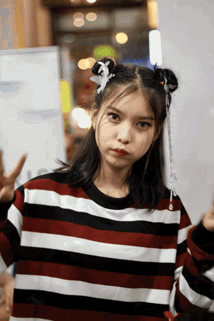a girl wearing a red and white striped shirt makes a peace sign