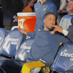 a man in a blue shirt sits in a row of elevate health chairs