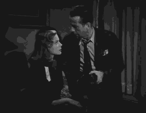 a man in a suit and tie stands next to a woman in a black dress